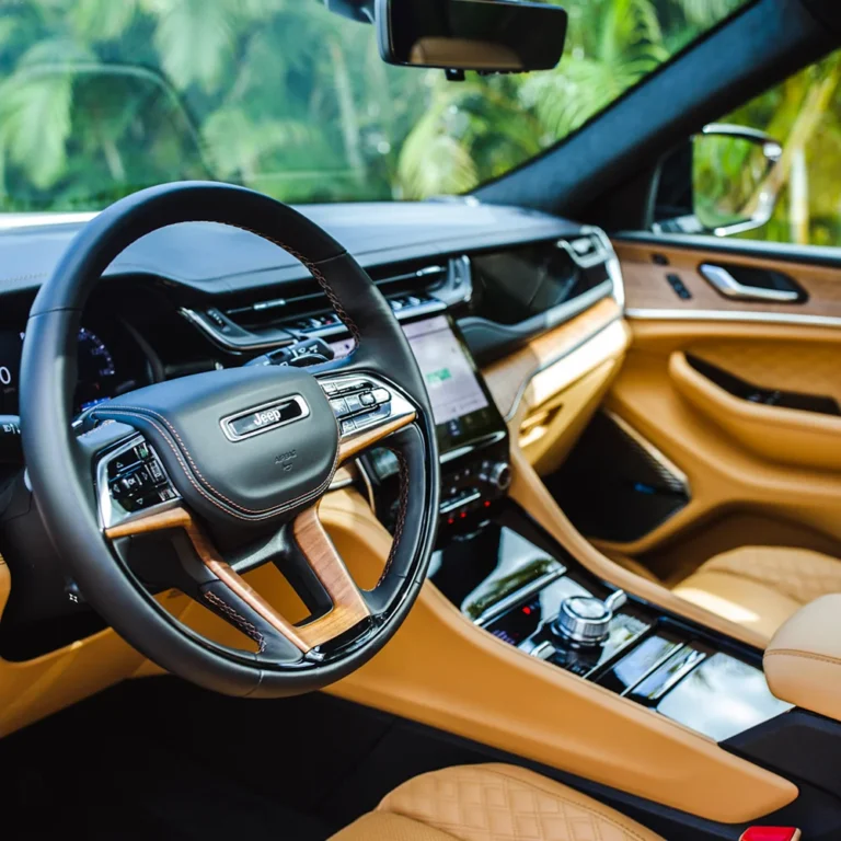Luxury Jeep interior featuring tan quilted leather seats, wood accents, and a high-tech dashboard with a large touchscreen display.