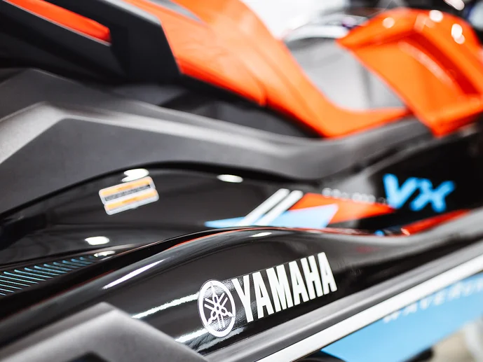 Close-up of a Yamaha VX personal watercraft in black with orange accents, showing the Yamaha logo and sleek body design.