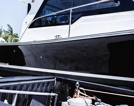 Close-up of a black and white motor yacht hull next to a dock with coiled ropes and boating equipment in the foreground.