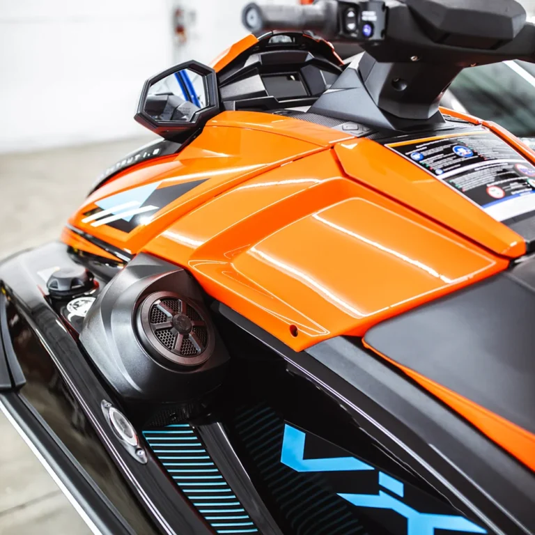 Close-up view of a Yamaha VX WaveRunner jet ski featuring an orange body, side mirror, and built-in speaker, highlighting its modern dashboard and sporty design.