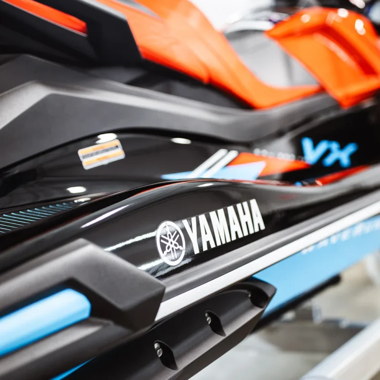 Close-up of a Yamaha WaveRunner VX personal watercraft featuring a glossy black and blue exterior with bold branding and red seat detailing.