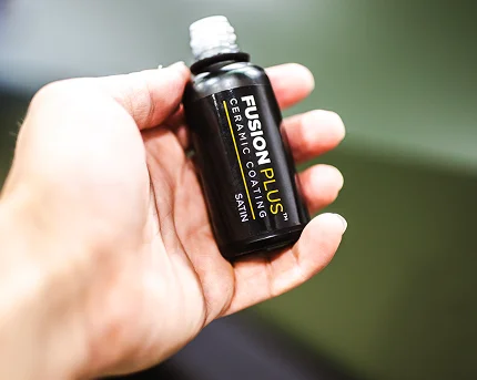 Hand holding a small bottle of Fusion Plus ceramic coating satin finish.