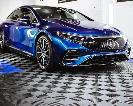 Shiny blue Mercedes-Benz sedan parked indoors on a patterned floor.