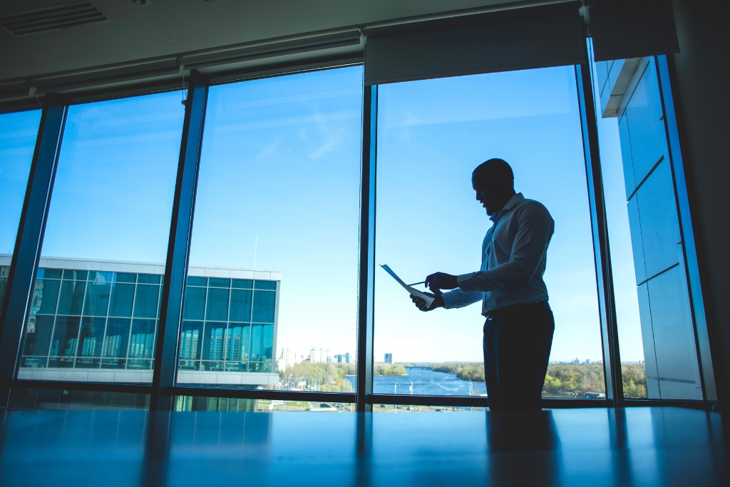 A business professional stands near large tinted office windows in Fort Myers, symbolizing the process of choosing the right tinting solution for comfort, energy efficiency, and privacy.