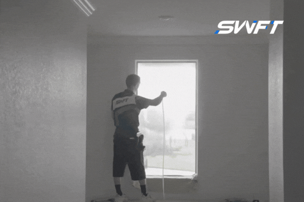 Technician from Southwest Florida Tinting inspecting a newly installed tinted window in a bright room, demonstrating tinted window maintenance tips beyond cleaning.