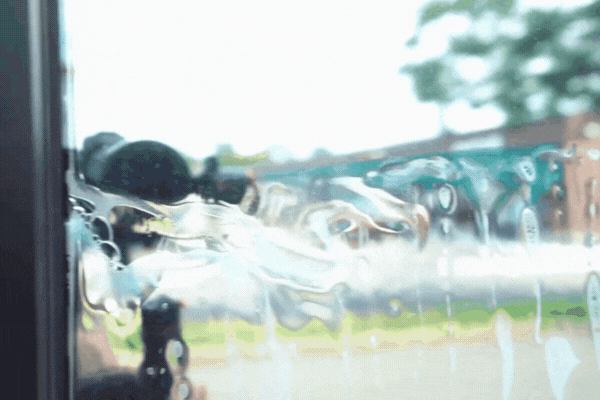 Close-up of a window in Fort Myers being tinted with a clear film, showing water and application tools in motion, visually explaining what is commercial window tinting.