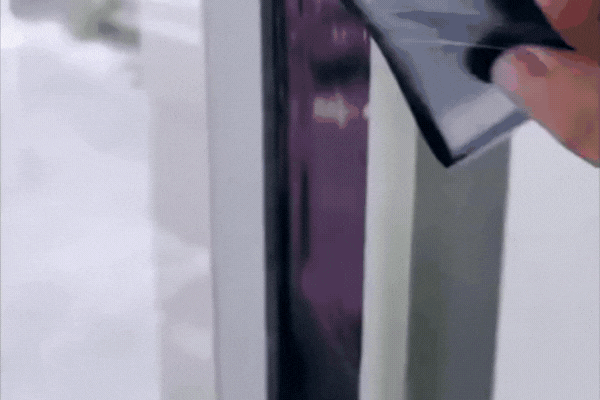 A Southwest Florida Tinting professional carefully applies a dark residential window film to a glass door, smoothing it along the edges to ensure a clean, secure fit. This process demonstrates how Residential Window Tinting Solutions enhance energy efficiency, UV protection, and home comfort in Fort Myers.