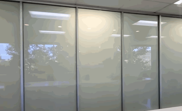 Glass panels in an office switch from transparent to opaque, showing the dynamic privacy control provided by smart window tinting.
